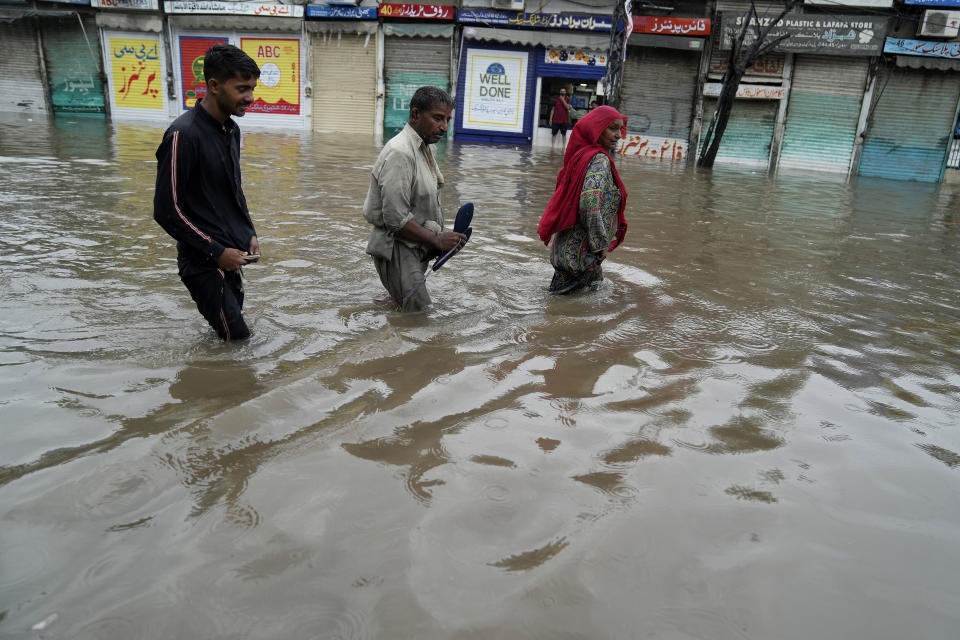 People wade through a flooded area caused by heavy monsoon rainfall in Lahore, Pakistan, Wednesday, July 5, 2023. Officials say heavy monsoon rains have lashed across Pakistan, killing a number of people. (AP Photo/K.M. Chaudary)