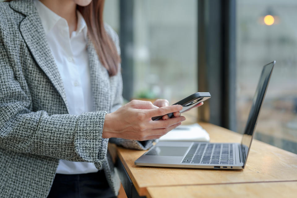 Close up of a woman using her smartphone to transact with a customer via the messaging app LINE, make a financial transaction and use social media.