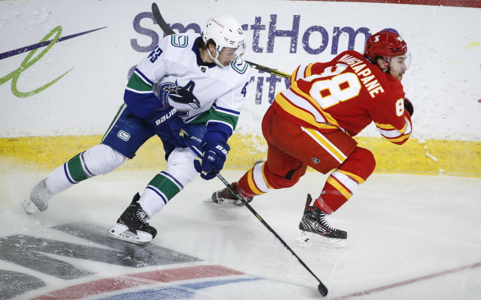 Vancouver Canucks' Quinn Hughes, left, watches as Calgary Flames' Andrew Mangiapane gets away from him during third-period NHL hockey game action in Calgary, Alberta, Monday, Jan. 18, 2021. (Jeff McIntosh/The Canadian Press via AP)