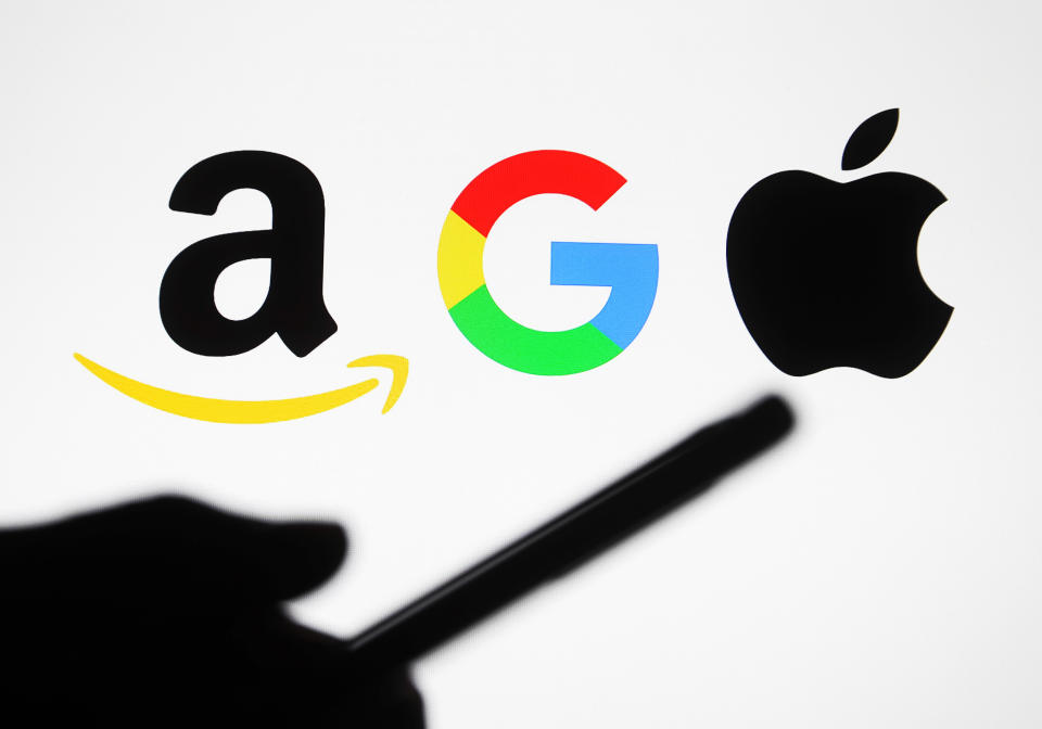 UKRAINE - 2021/01/10: In this photo illustrative Google, Amazon and Apple logos are seen behind a silhouette of a hand holding a mobile phone. (Photo Illustration by Pavlo Gonchar/SOPA Images/LightRocket via Getty Images)