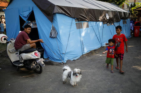 A man holds his dog on a leash outside a tent at a temporary evacuation center for people living near Mount Agung, a volcano on the highest alert level, in Manggis, on the resort island of Bali, Indonesia, September 28, 2017. REUTERS/Darren Whiteside