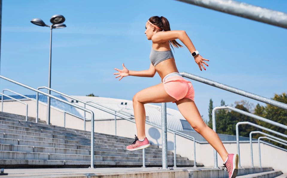 A woman jogging up a set of stairs outdoors.