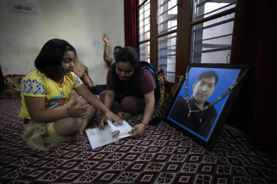 Kritika Bhat studies in front of a portrait of her father Rahul Bhat in Jammu, India, June 11, 2022. A Kashmiri Hindu Rahul Bhat was killed by militants in Budgam district. Bhat worked with the revenue department in the Tehsildar office at Chadoora in Budgam. When he was in the office on that day, terrorists had fired at him in the office premises. (AP Photo/Channi Anand)