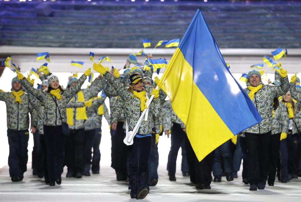 Valentina Shevchenko of Ukraine carries the national flag as she leads the team during the opening ceremony of the 2014 Winter Olympics in Sochi, Russia, Friday, Feb. 7, 2014. (AP Photo/Mark Humphrey)