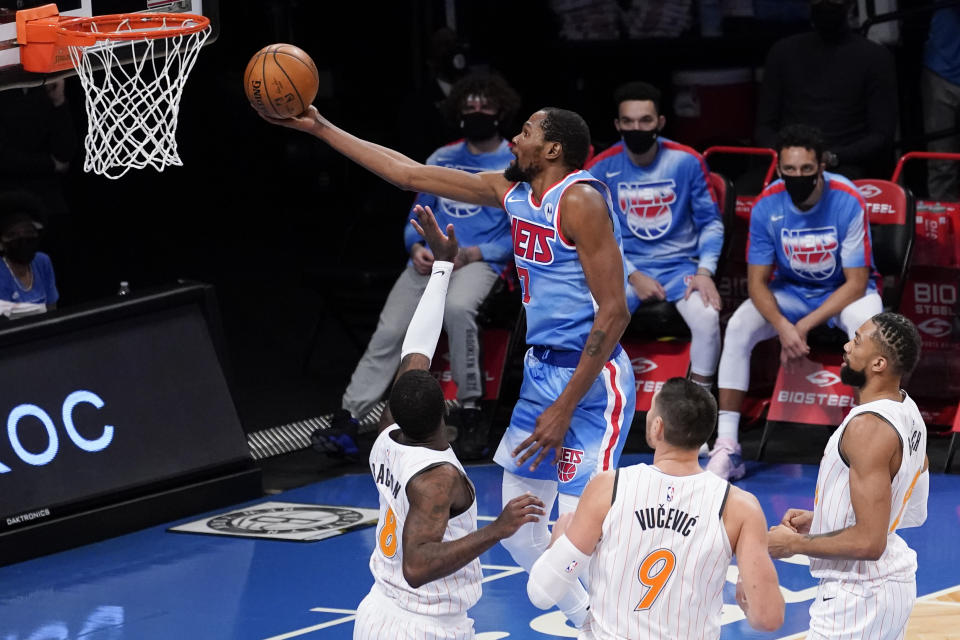 Brooklyn Nets forward Kevin Durant (7) goes to the basket past Orlando Magic forward Dwayne Bacon (8) center Nikola Vucevic (9) and center Khem Birch (24) during the second half of an NBA basketball game, Saturday, Jan. 16, 2021, in New York. (AP Photo/Mary Altaffer)