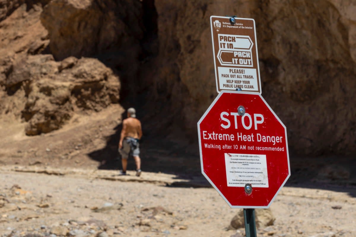 A hiker passes a sign warning of extreme heat at the start of the Golden Canyon trail, in Death Valley National Park, where a motorcylist died from extreme heat on July 6  (AP)