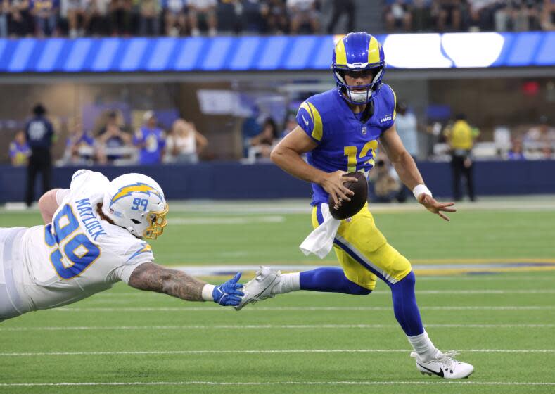 INGLEWOOD, CA - AUGUST 12: Rams quarterback Stetson Bennett scrambles away fron Chargers Scott Matlock.