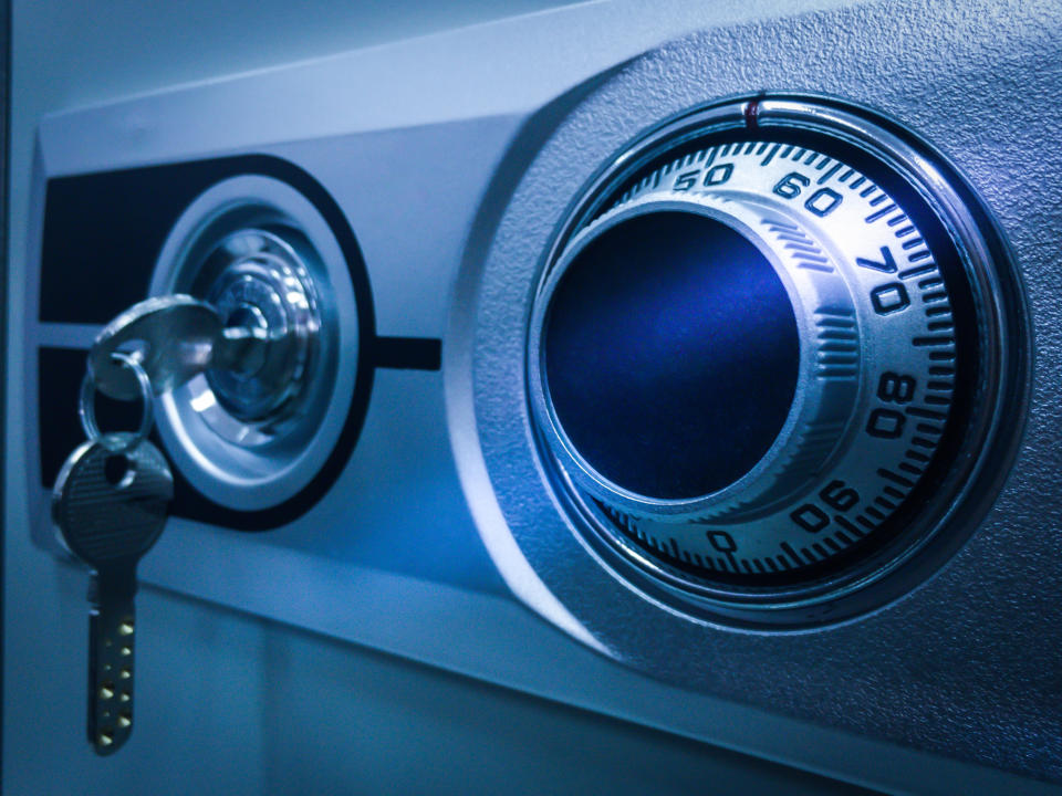 A close-up image of a safe lock with a combination dial and a key inserted into the keyhole. This image relates to security and financial protection