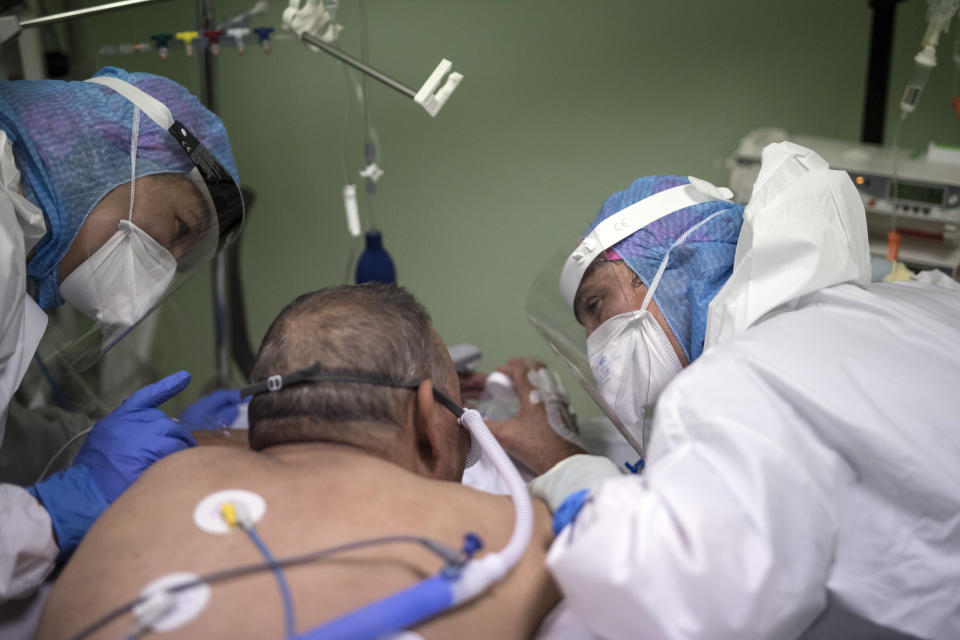 Nurses comfort a COVID-19 patient in the intensive care unit at the Joseph Imbert Hospital Center in Arles, southern France, Wednesday, Oct. 28, 2020. Many French doctors are urging a new nationwide lockdown, noting that 58% of the country's intensive care units are now occupied by COVID patients and medical staff are under increasing strain. (AP Photo/Daniel Cole)