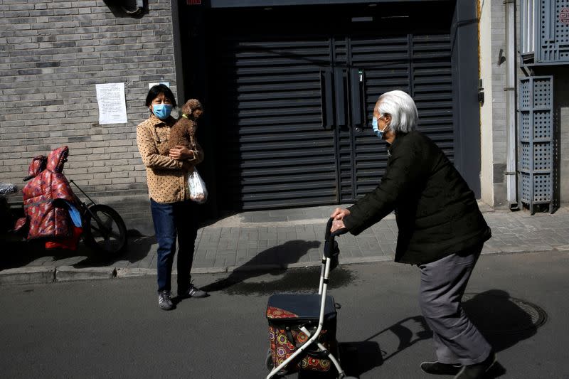 Woman wearing a face mask observes a moment of silence while holding her dog in Beijing