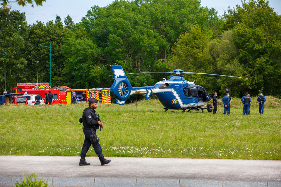 French gendarmes and firemen stand near helicopters in La Chapelle-sur-Erdre, France, Friday, May 28, 2021. An unidentified assailant stabbed a police officer at her station Friday in western France then shot two other officers before being killed in a shootout with police, authorities said. (AP Photo/Laetitia Notarianni)