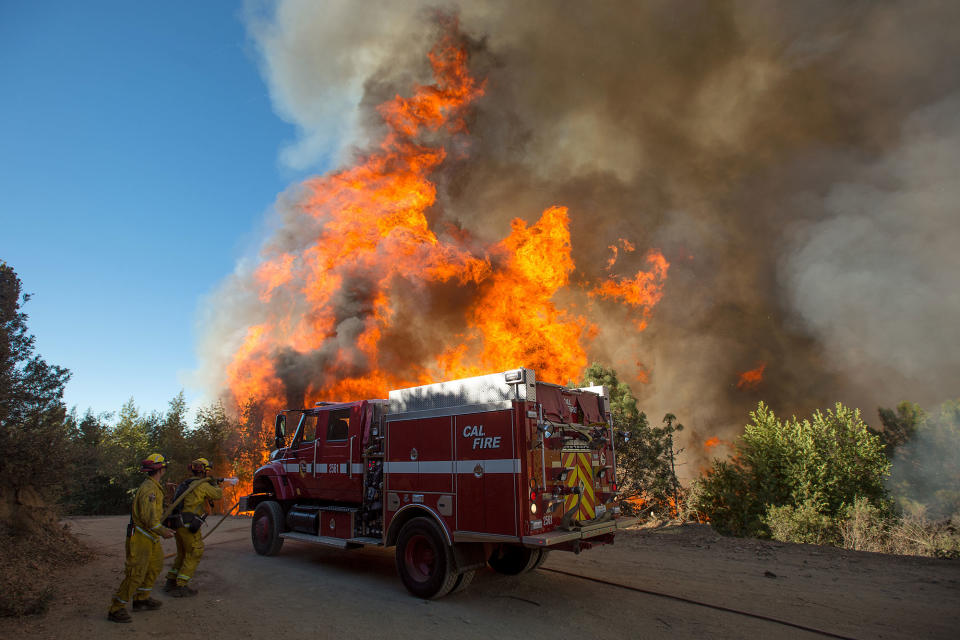 <p>Flames from a wildfire tower above firefighters as they try to stop the blaze from crossing Loma Prieta Ave. near Morgan Hill, Calif., on Tuesday, Sept. 27, 2016. (AP Photo/Noah Berger) </p>
