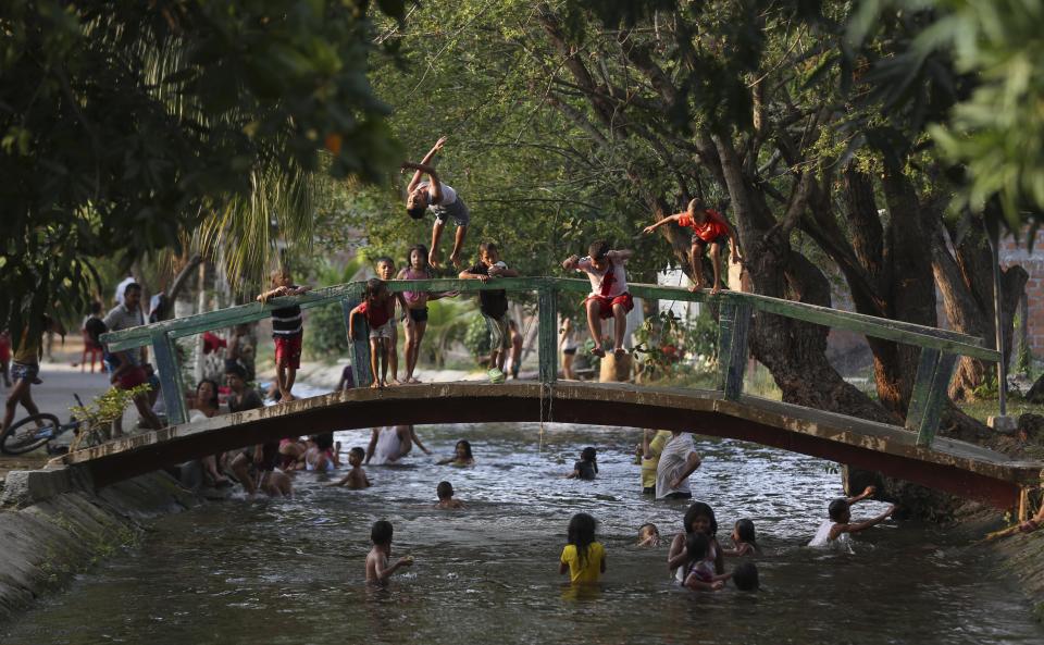 Children play in an irrigation canal, the local swimming hole that runs though Aracataca, the hometown of the late Nobel laureate Gabriel Garcia Marquez along Colombia's Caribbean coast during the Holy Week holiday on Friday, April 18, 2014. Although the author evoked his homeland's beauty in his novels and visited frequently, he never again resided there permanently, instead spending his time in Europe and Mexico City, where his cremated remains will be displayed at a memorial service Monday. Garcia Marquez died on Thursday in Mexico City. (AP Photo/Ricardo Mazalan)