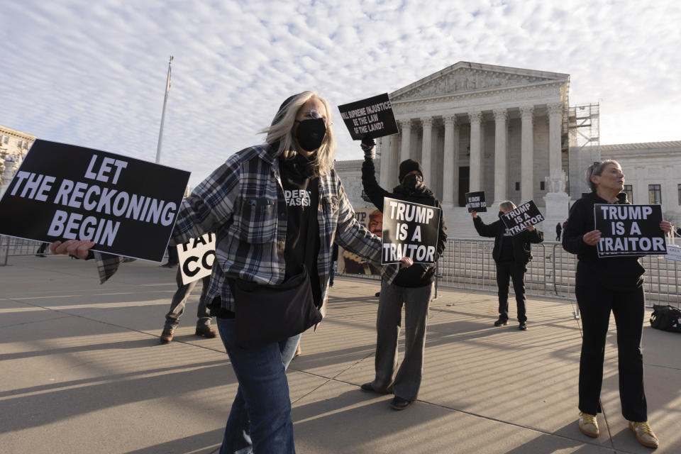 Myra Slotnick of Provincetown, Mass., holds placards in front of the U.S. Supreme Court, Thursday, Feb. 8, 2024, in Washington. The U.S. Supreme Court on Thursday will take up a historic case that could decide whether Donald Trump is ineligible for the 2024 ballot under Section 3 of the 14th Amendment. (AP Photo/Manuel Balce Ceneta)