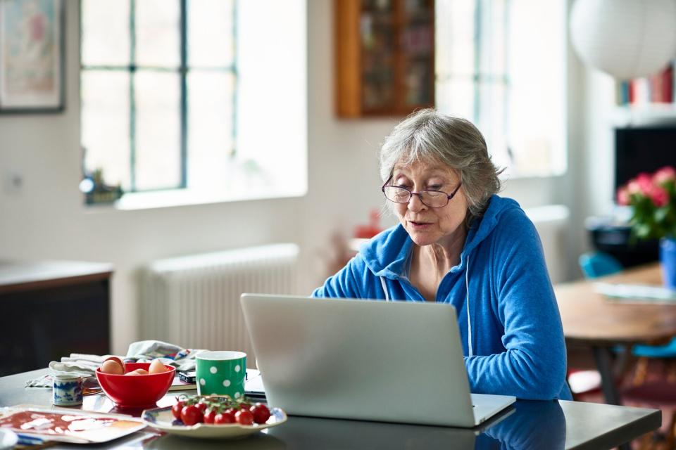 Senior woman wearing glasses using laptop at home