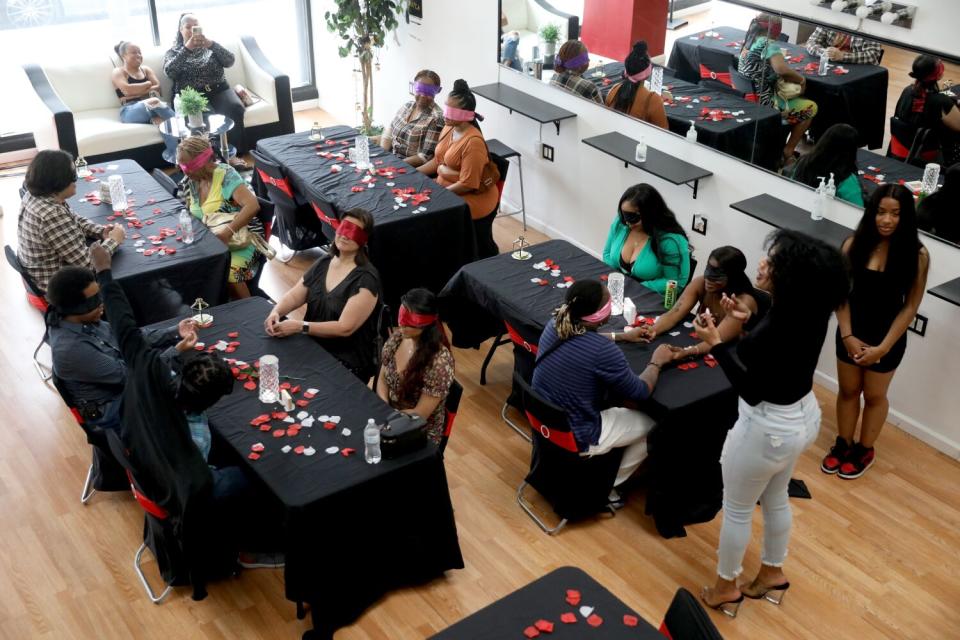 Blindfolded people sit at tables during a speed-dating event.