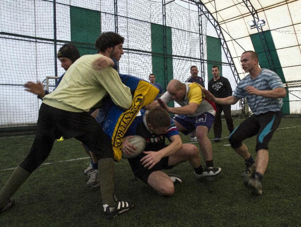 In this photo taken on Sunday, Feb. 2, 2014, members of the Kosovo Roosters Rugby team train on an indoor pitch in Mitrovica, Kosovo. They've been roughing each other up for almost a century without any rules. But, now Serbs and Albanians are tackling a new form to deal with old enmities. Spurred by a group of aid workers they are learning to work together through a sport that is all about gaining territory: rugby. In Mitrovica, a city that has come to symbolize the ethnic split, youths from both side of the divide gather to train and follow instructions from their French, Irish and American trainers. (AP Photo/Visar Kryeziu)