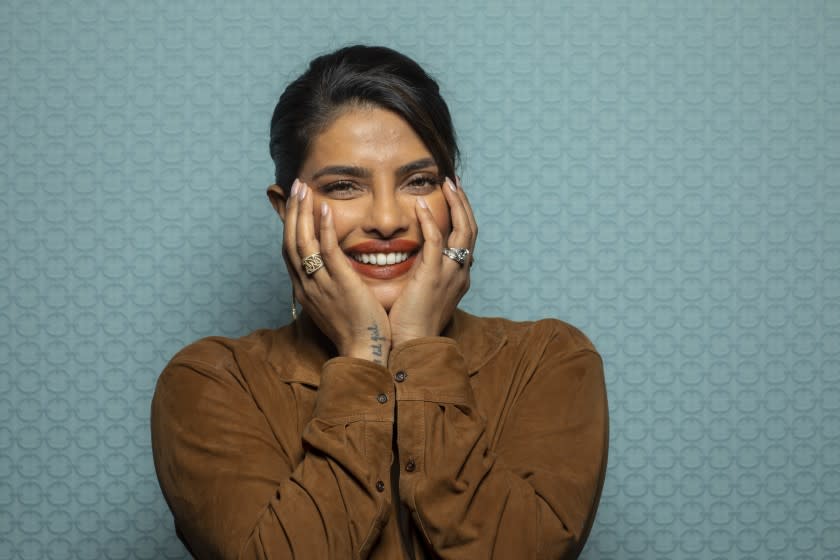 A woman smiles with hands on her face