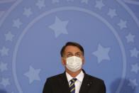 Brazil's President Jair Bolsonaro wearing a protective mask to curb the spread of the new coronavirus, attends the launching ceremony of a rights guarantee program for rural women, at the Planalto Presidential Palace in Brasilia, Brazil, Wednesday, July 29, 2020. (AP Photo/Eraldo Peres)