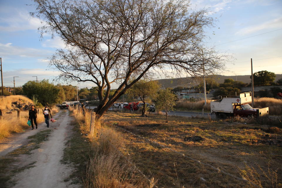 Locals walk past an abandoned truck that was modified into a ram, found on the outskirts of Tula after a gang rammed several vehicles into a prison and escaped with nine inmates, in Tula, Mexico, Wednesday, Dec. 1, 2021. (AP Photo/Ginnette Riquelme)