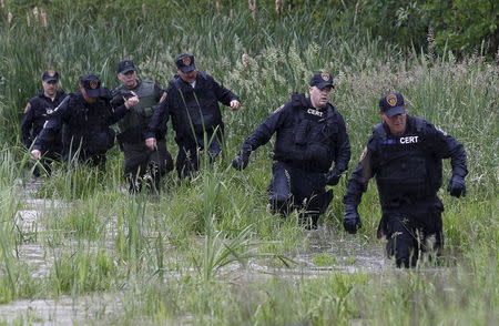 Law enforcement officers walk in water while searching a field near Willsboro, New York June 9, 2015. REUTERS/Chris Wattie