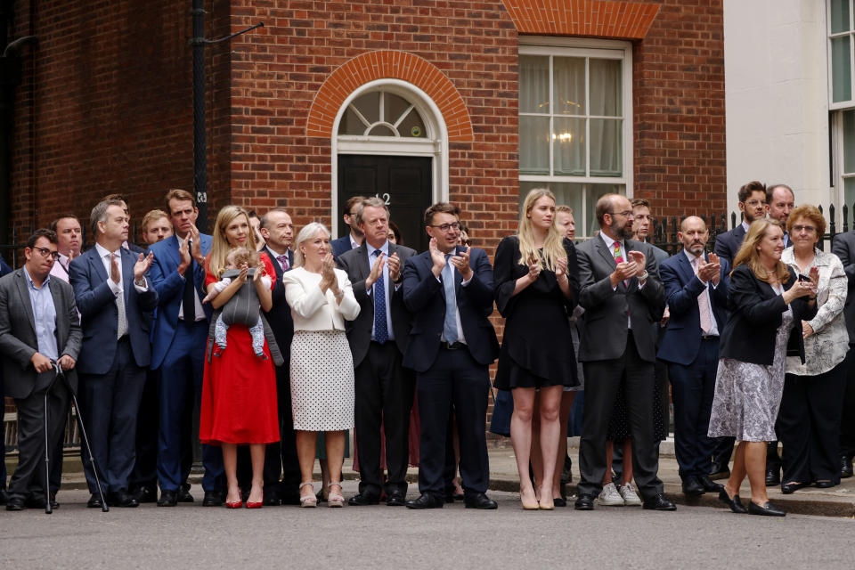 Onlookers, including Carrie Johnson, and baby Romy, Culture Secretary Nadine Dorries and Scotland Secretary Alister Jack watch as British Prime Minister Boris Johnson addresses the nation to announce his resignation outside 10 Downing Street, on July 7, in London. (Dan Kitwood / Getty Images)