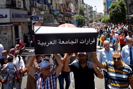 Palestinian demonstrators carry a symbolic coffin reading: "the resolutions of the Arab League" during a protest against Bahrain's workshop for U.S. peace plan, in Ramallah, in the Israeli-occupied West Bank