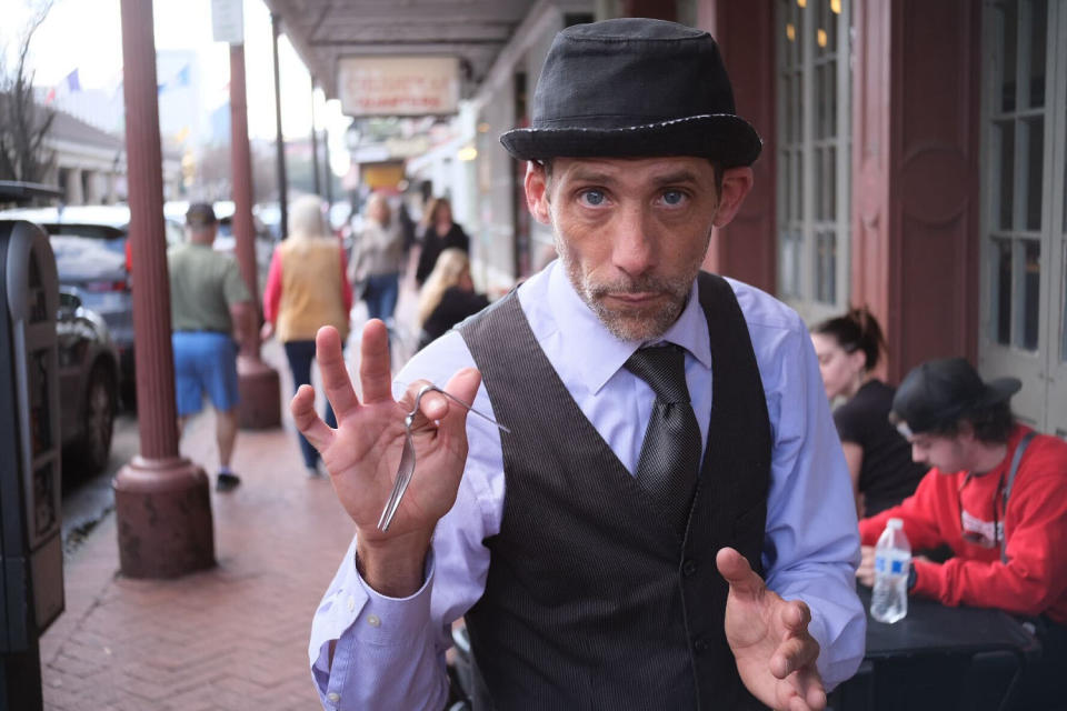 Man in street balancing a bent fork over his forefinger (Alex Seitz-Wald / NBC News)