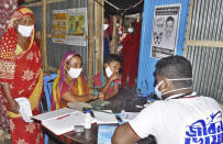 In this photo provided by Bidyanondo Foundation, a doctor writes a prescription for a patient after arriving at Banishanta village near Mongla seaport in southwestern region of Bangladesh, Sept. 1, 2020. A Bangladeshi charity has set up a floating hospital turning a small tourist boat into a healthcare facility to provide services to thousands of people affected by this year's devastating floods that marooned millions. (Bidyanondo Foundation via AP)