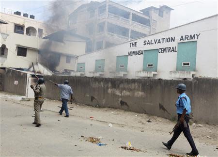 Armed policemen walk past a Salvation Army Church compound set on fire by youths after a protest against the killing of an Islamic cleric in the coastal Port town of Mombasa October 4, 2013. REUTERS/Joseph Okanga