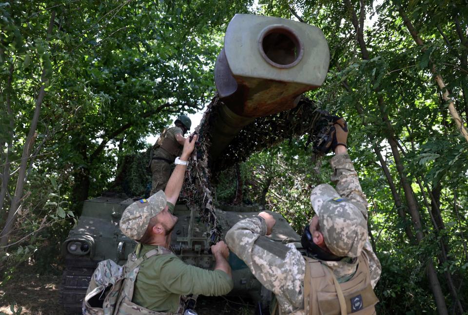 Ukrainian marines from the 37th Brigade install camouflage netting on an M109 155 mm self-propelled howitzer at a position in the Donetsk region on July 10, 2023, amid the Russian invasion of Ukraine.