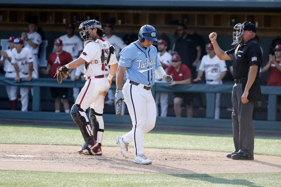 North Carolina's Alberto Osuna, center, walks back to the dugout after striking out in the eighth inning with Arkansas' Michael Turner, left, nearby during an NCAA college super regional baseball game in Chapel Hill, N.C., Sunday, June 12, 2022. (AP Photo/Karl B DeBlaker)