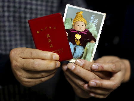 Jiang Weimao, 60, and his wife Zhang Yinxiu, 53, show a picture of their dead son as a baby and his "honourable single child certification" at their house in in Zhangjiakou, China, November 21, 2015. Jiang and Zhang's son, Jiang Tingyi, was born in 1984 and died of diabetes in 2010. They recall the propaganda slogan in the 1980s: "Only having one child is good, the state will take care of the elderly." They both worked in the same glass factory and didn't think of having a second baby for fear of losing their job. Zhang had an abortion after falling pregnant a second time. Now retired, they live with Zhang's parents on the outskirts of Zhangjiakou city. The son's struggles with diabetes left them in heavy debt. Now they live on a pension but it's not enough to cover the family's medical bills. Zhang said the change of the one-child policy has nothing to do with them and has only deepened their sorrow caused by the loss of their only child. REUTERS/Kim Kyung-Hoon