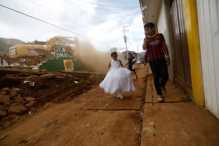 A girl in a communion dress walks past a demolition machine tearing down a house damaged by an earthquake, in Tecomatlan, Mexico. REUTERS/Edgard Garrido