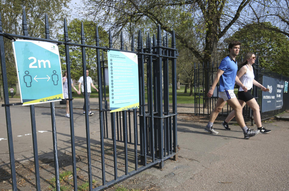 Signs on the gates reminding people to 'social-distance' at Victoria Park, in east London, after it was reopened with reduced opening hours and new control measures in place during the coronavirus outbreak, Saturday April 11, 2020. The park was closed on 25 March after the "failure of some visitors to follow social-distancing guidance", but the local council has now reopened the facility. The highly contagious COVID-19 coronavirus has impacted on nations around the globe, many imposing self isolation and exercising social distancing when people move from their homes. (Jonathan Brady / PA via AP)