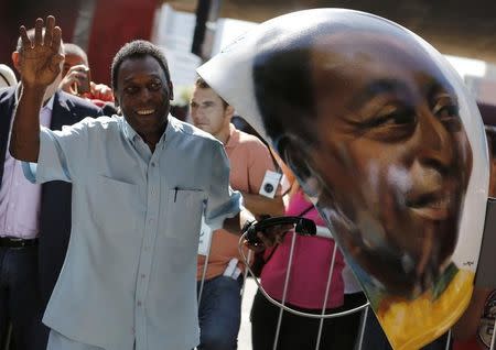 Brazilian soccer legend Pele waves next to a public telephone booth with an image of his face painted by Brazilian artist Sipros after he autographed it, during the Call Parade art exhibition in Sao Paulo May 8, 2014. REUTERS/Nacho Doce