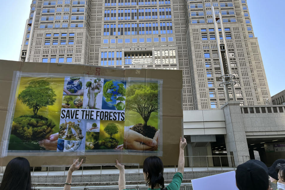 People gather in front of the Tokyo Metropolitan Government Building in Tokyo, Sunday, April 9, 2023, as they protest against the Meiji Jingu Gaien area redevelopment project. An area known as Jingu Gaien is famous for a row of about 150 ginko trees. The redevelopment plans call for razing a historic baseball stadium and a neighboring rugby stadium in the area and rebuilding them in different spots in the reconfigured space, making room for a pair of towering skyscrapers and a shopping area. (AP Photo/Stephen Wade)