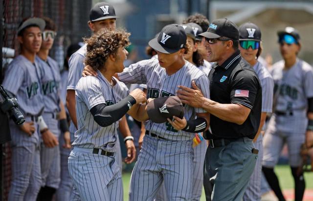 Varela Varsity Vipers Sebastian Gonzalez (12) is held back by teammates as Gonzalez interacts with a game official during an incident involving fans in the third inning in the game against the Doral Firebirds at Doral Academy in Doral on Saturday, May 13, 2023.