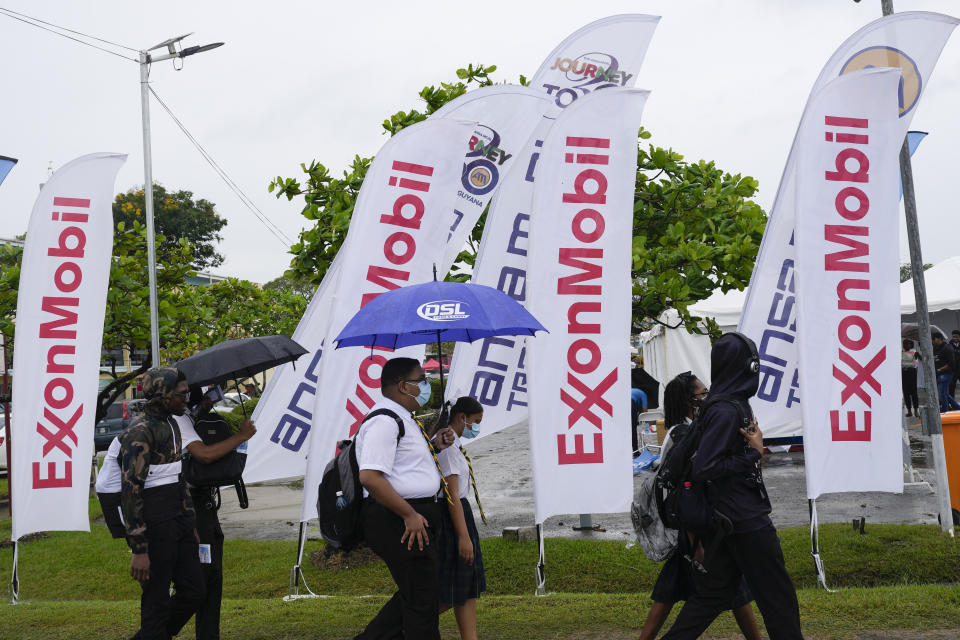 File - High school students walk past ExxonMobil flags as they arrive to a job fair at the University of Guyana in Georgetown, Guyana, April 21, 2023. Exxon Mobil reports earnings on Friday, Oct. 27, 2023 (AP Photo/Matias Delacroix, File)