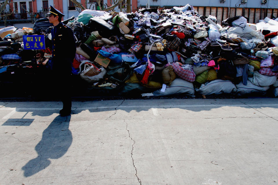 SHANGHAI, CHINA - FEBRUARY 23:  (CHINA OUT) A local policeman looks on in front of a wall of counterfeit products on February 23, 2011 in Shanghai, China. Products from brands such as Louis Vuitton, Burberry, Armarni and North Face were destroyed as Shanghai Industrial and Commercial authorities destroyed more than 425,700 fake products on Wednesday. As fake products increase, the bureau will continue to track down on fake markets.  (Photo by VCG/VCG via Getty Images)