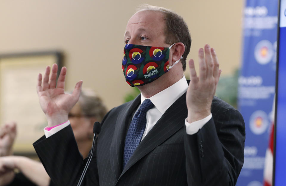 Colorado Governor Jared Polis dons a mask to encourage state residents to wear them while in public as a statewide stay-at-home order remains in effect in an effort to reduce the spread of the new coronavirus Friday, April 3, 2020, in Centennial, Colo. The new coronavirus causes mild or moderate symptoms for most people, but for some, especially older adults and people with existing health problems, it can cause more severe illness or death. (AP Photo/David Zalubowski)