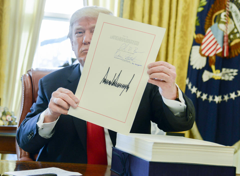 President Trump holds up a tax-overhaul bill after signing it into law, Dec. 22, 2017. (Photo: Mike Theiler/Pool via Bloomberg)