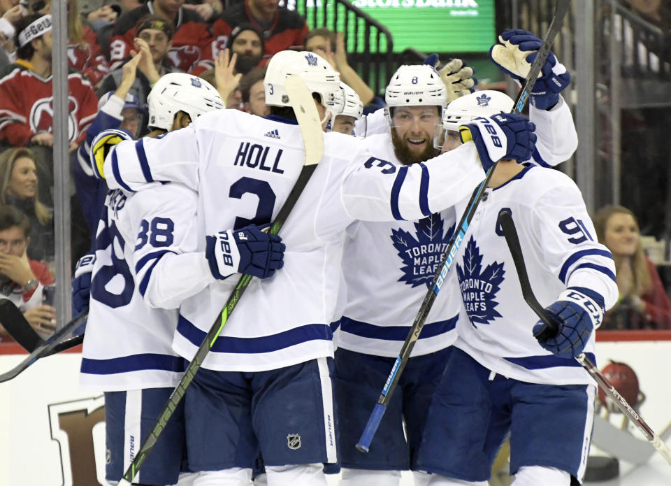 Toronto Maple Leafs' William Nylander (88), Justin Holl (3), Jake Muzzin (8) and John Tavares (91) surround Ilya Mikheyev to celebrate his goal during the first period of an NHL hockey game against the New Jersey Devils, Friday, Dec. 27, 2019, in Newark, N.J. (AP Photo/Bill Kostroun)