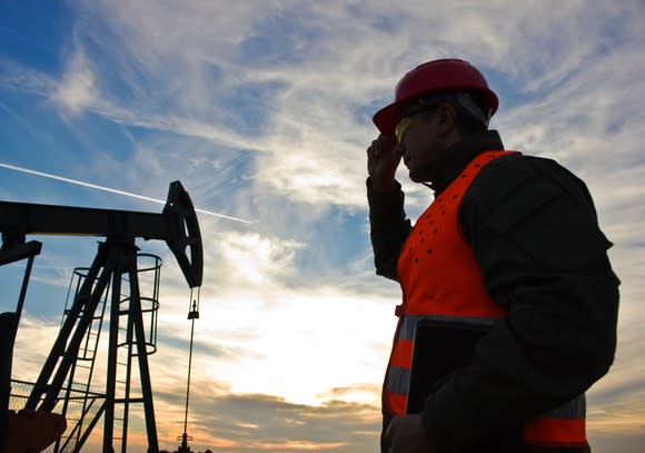 Oil Industry pump jack with one oil worker and laptop.