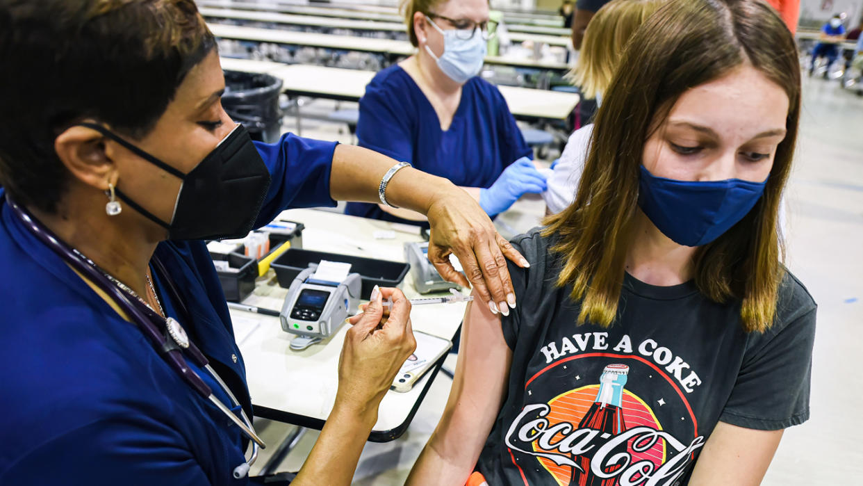 A nurse gives a dose of the Pfizer vaccine to a student