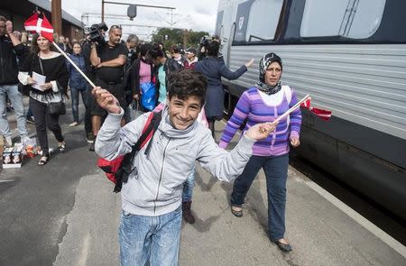 A boy waves Danish flags as he joins fellow migrants, mainly from Syria, on Padborg station to board a train heading to Sweden September 10, 2015. REUTERS/Claus Fisker/Scanpix Denmark