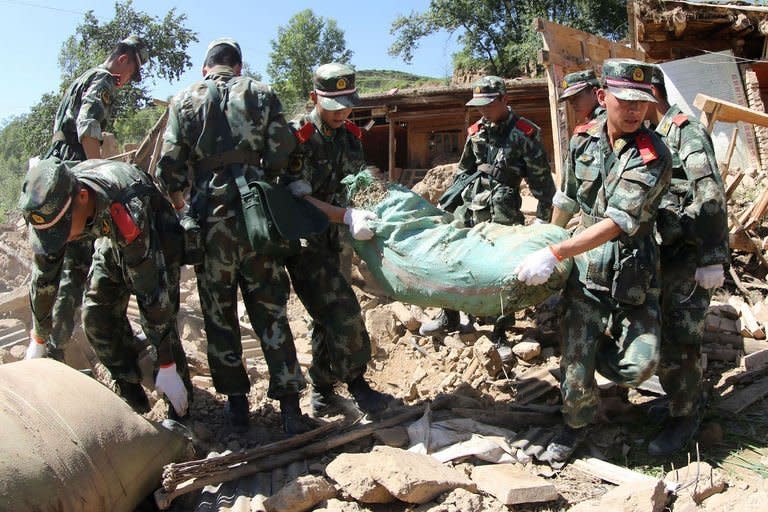 Rescuers work in the ruins of a damaged house in Hetuo township in Dingxi, northwest China's Gansu province on July 22, 2013. The traumatised survivors of two shallow earthquakes that killed at least 94 people in China have begun burying their dead, as they struggled with the devastation left behind