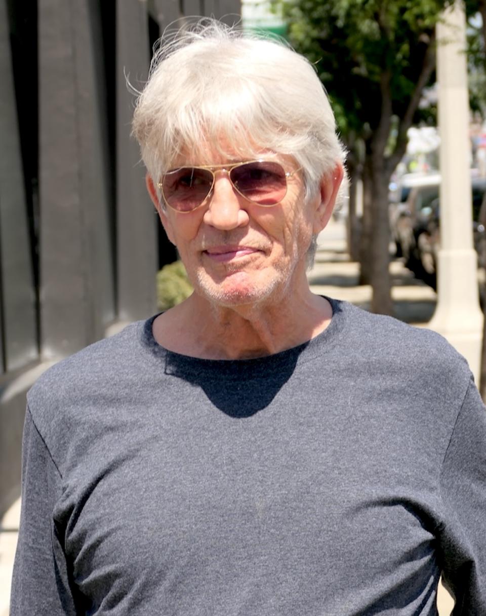 Eric Roberts is outdoors wearing sunglasses and a casual, long-sleeve shirt