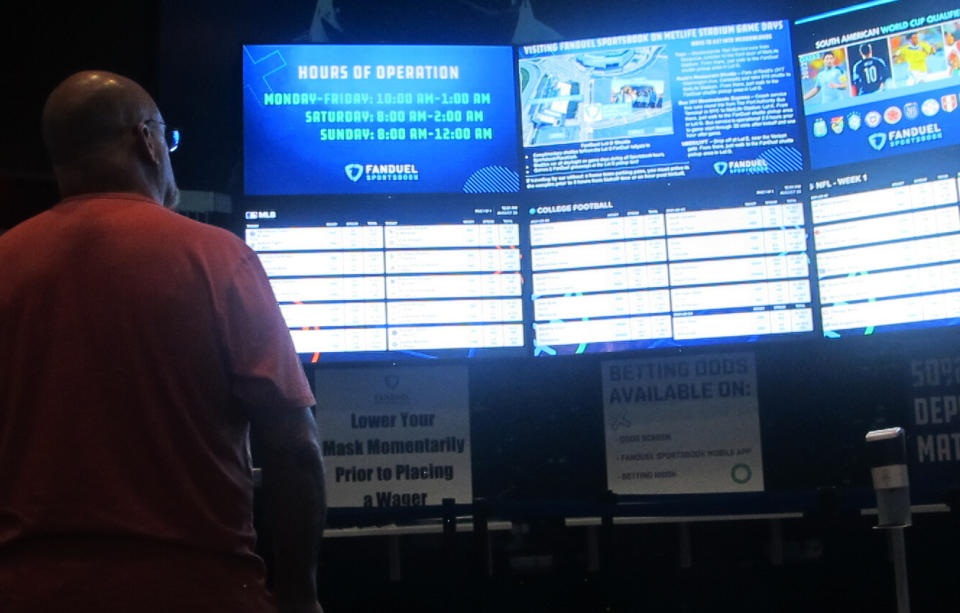 A gambler checks the odds boards at the FanDuel sportsbook in East Rutherford N.J. on Aug. 30, 2021. Tyhe American Gaming Association says 45.2 million Americans plan to bet on NFL games this season, up 36% from last year. (AP Photo/Wayne Parry)