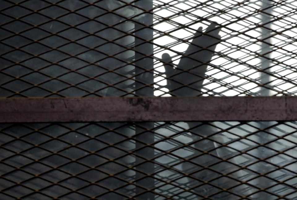 FILE - In this Aug. 22, 2015, file photo, a member of the Muslim Brotherhood waves his hand from a defendants cage in a courtroom in Torah prison, southern Cairo, Egypt. A report released by Amnesty International Wednesday, April 21, 2021, said the number of executions worldwide in 2020 plummeted to its lowest level in at least a decade. But the report said four states in the Middle East — Iran, Egypt, Iraq and Saudi Arabia respectively — topped the global list and pressed on with shootings, beheadings and hangings, ignoring pleas by rights groups to halt executions during the pandemic. (AP Photo/Amr Nabil, File)